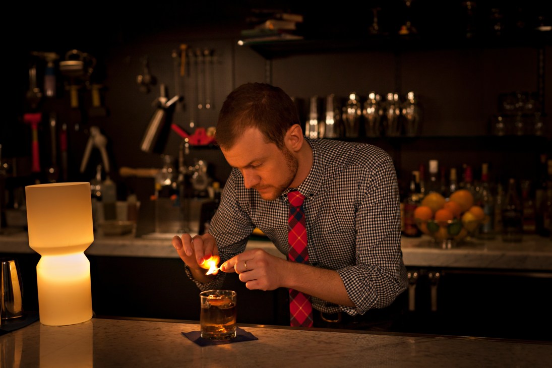 Bartender in checkered shirt and red tie crafting a cocktail at Marvel Bar in Minneapolis.