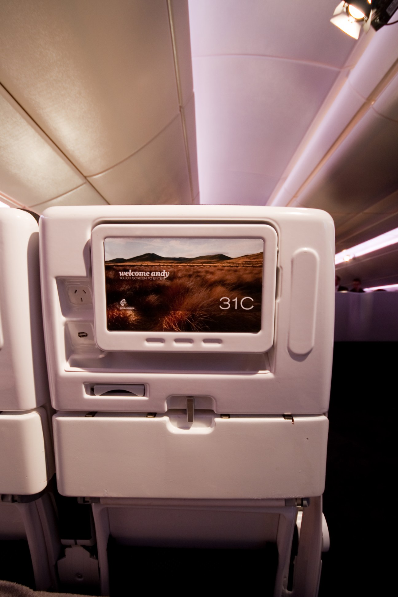 Air New Zealand economy seat in-flight entertainment screen displaying welcome message and temperature reading.