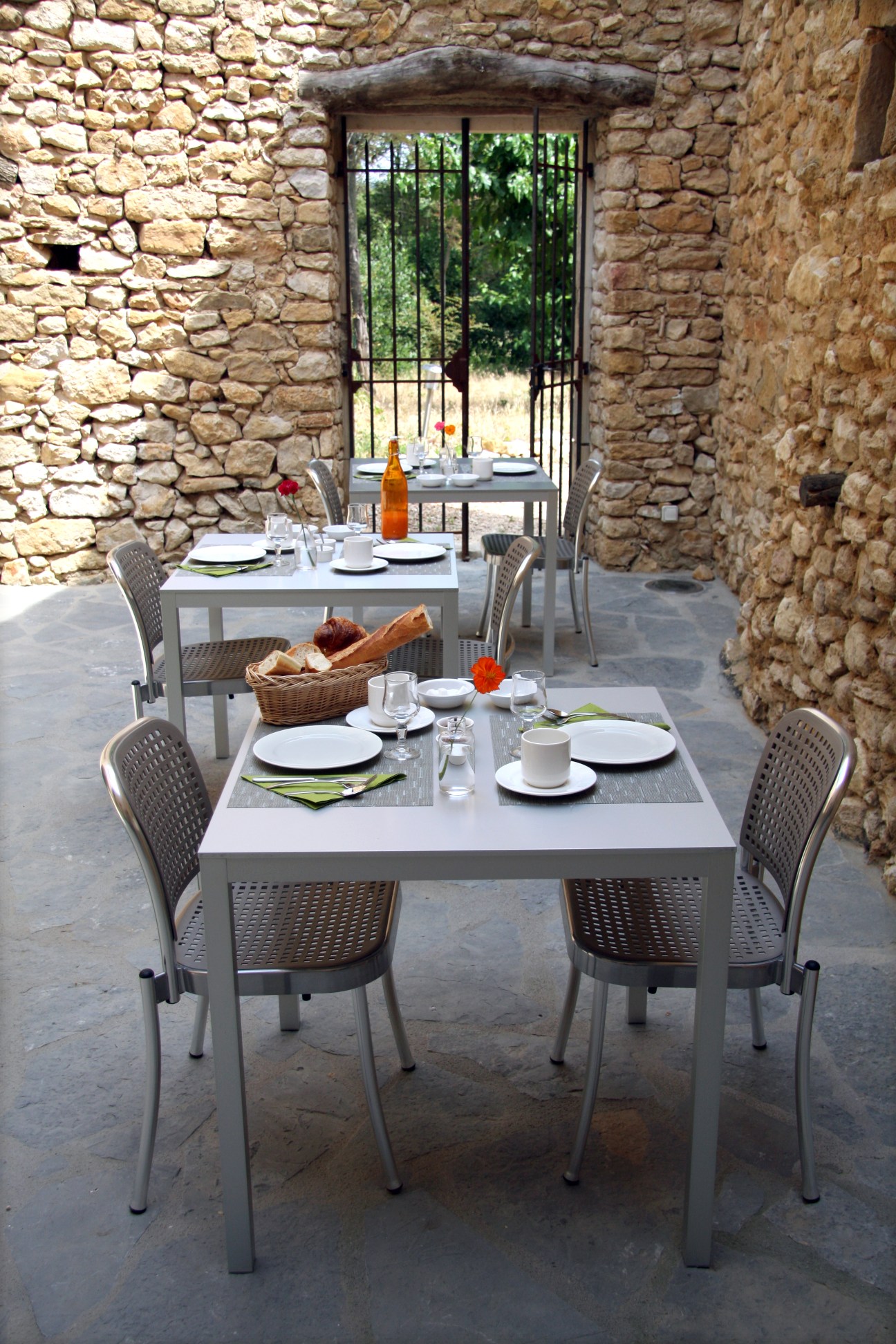 Outdoor dining area at La Maison d'Ulysee with stone walls and set tables.