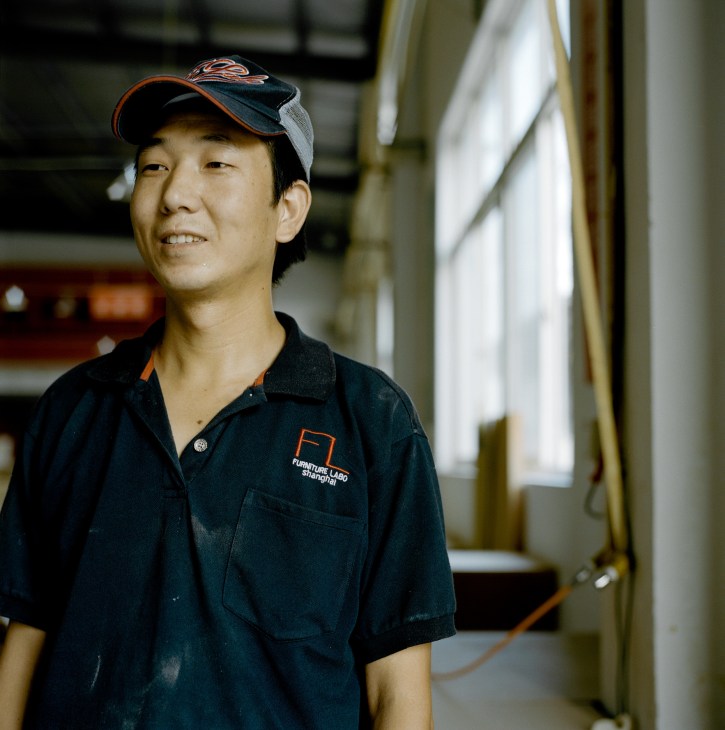 A Furniture Labo factory worker in Shanghai wearing a dark blue work uniform and cap.