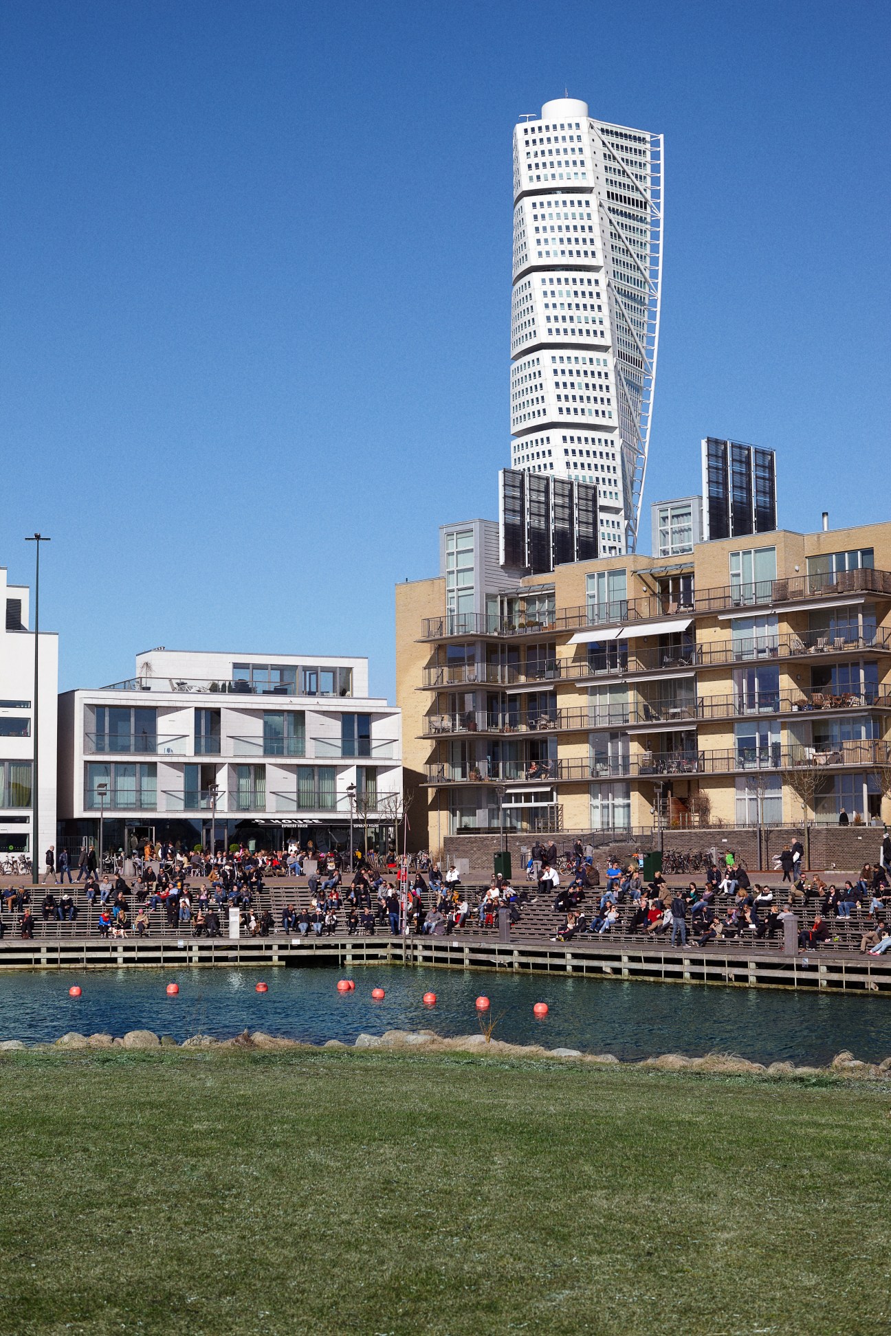 Malmö's Västra Hamnen waterfront with Santiago Calatrava's white Turning Torso tower rising behind residential buildings and public spaces.