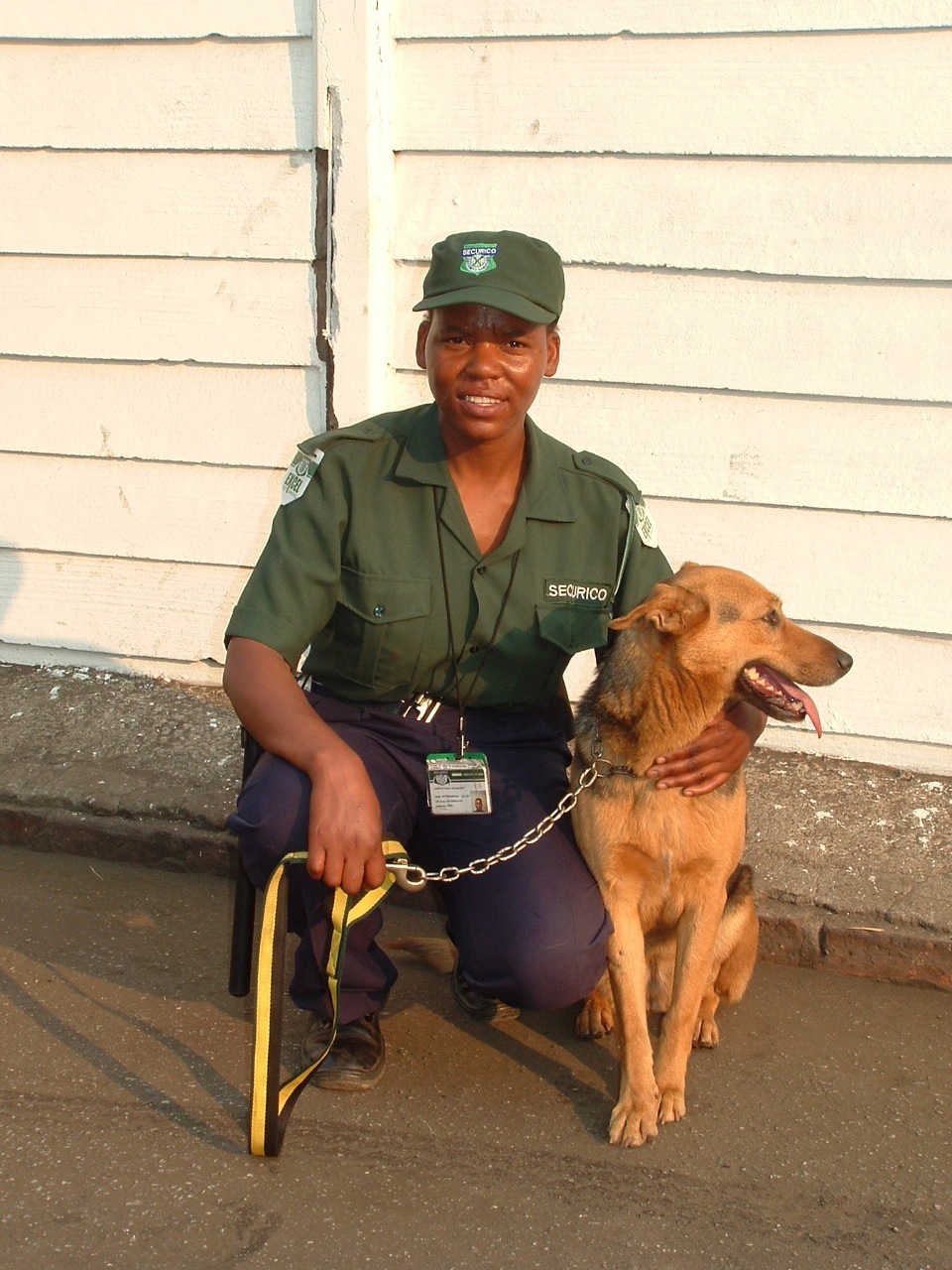 Female security guard in Securico uniform posing with a brown dog.