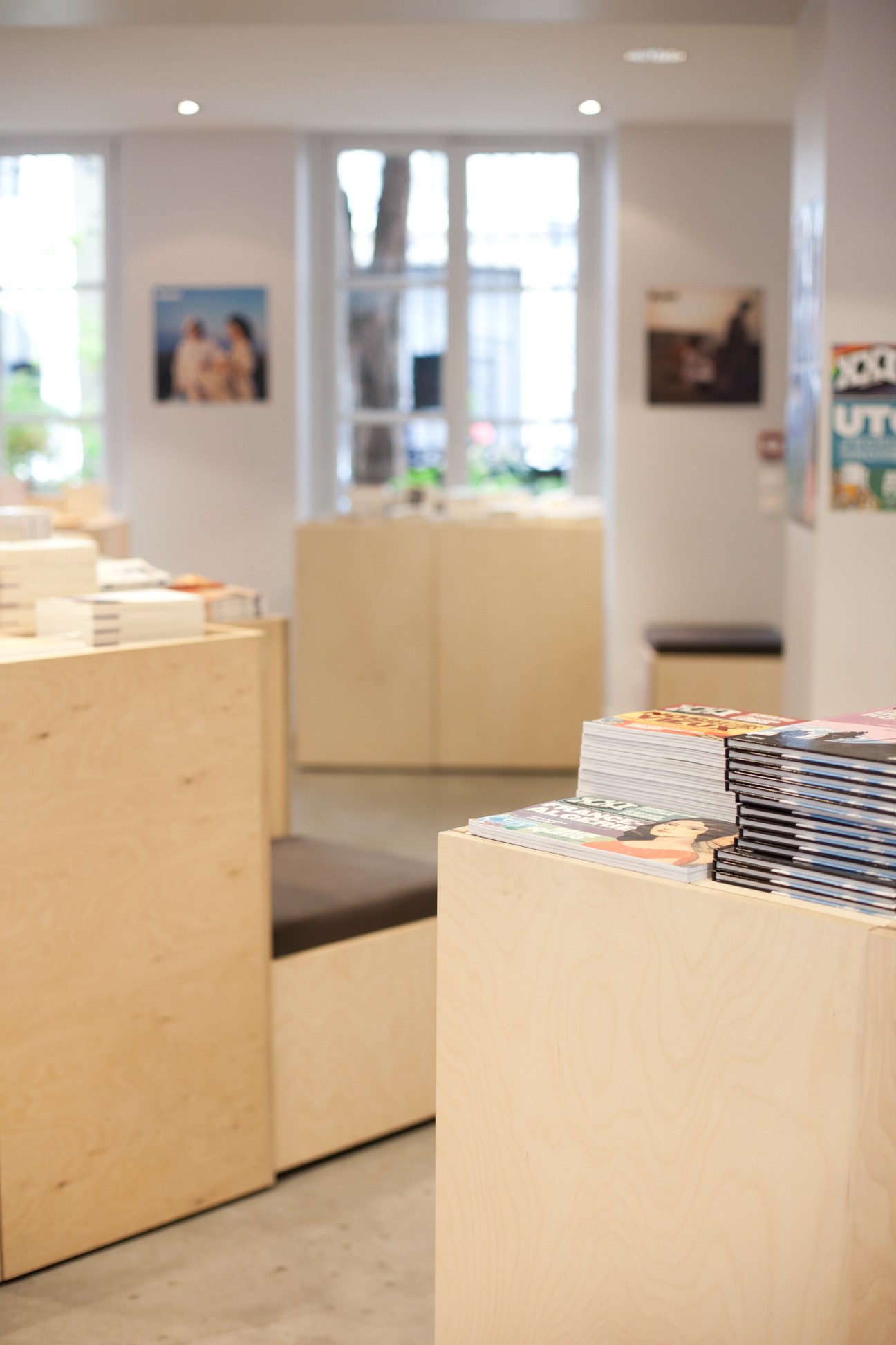 XXI magazines stacked on wooden display blocks in a bright, minimalist bookshop interior with large windows.