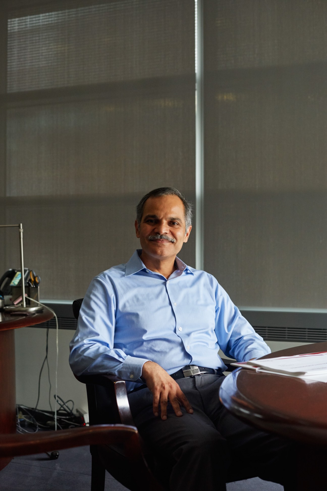 Amir Asif seated at desk in modern office with large windows