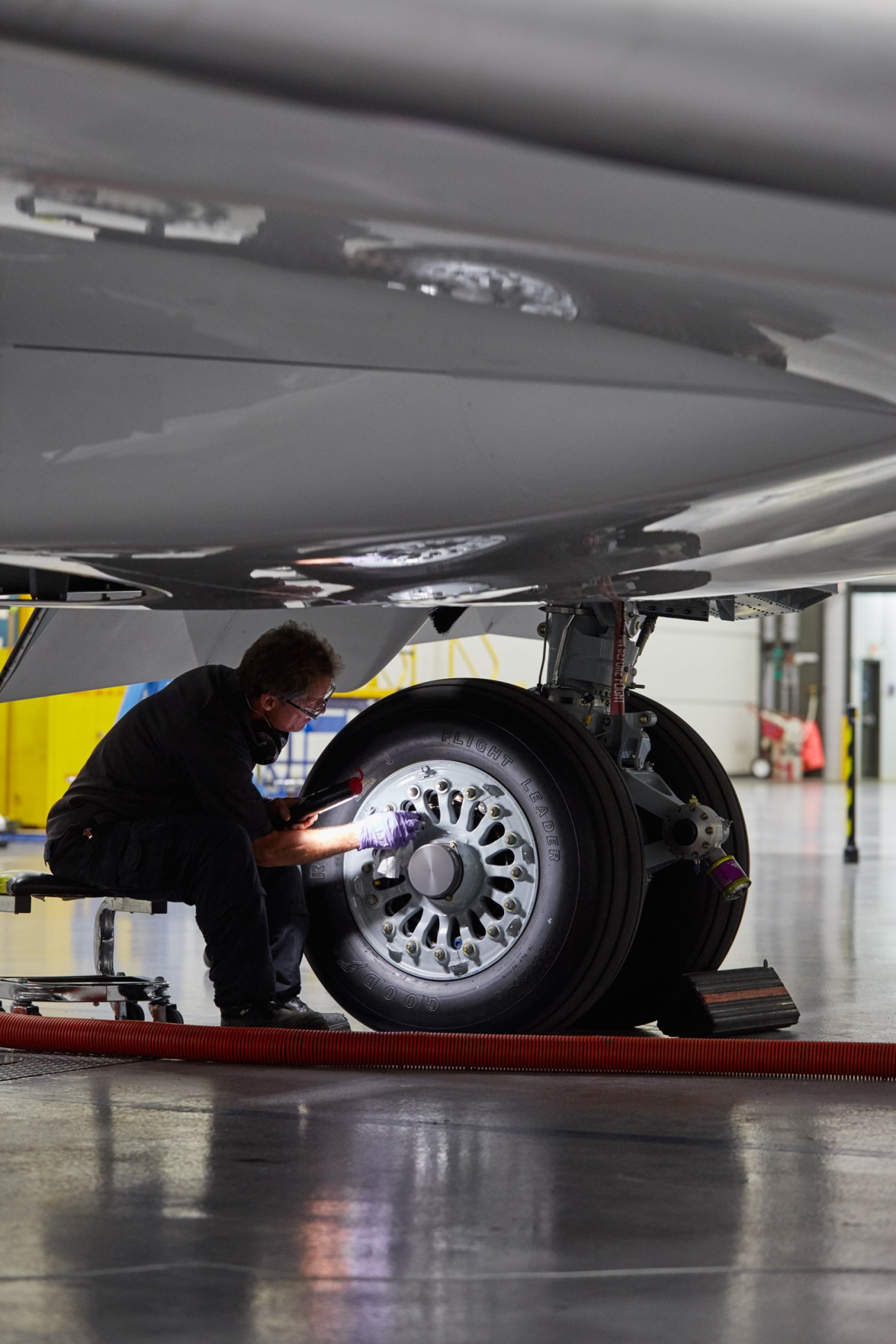 Technician working on aircraft landing gear underneath Bombardier CRJ900 in hangar