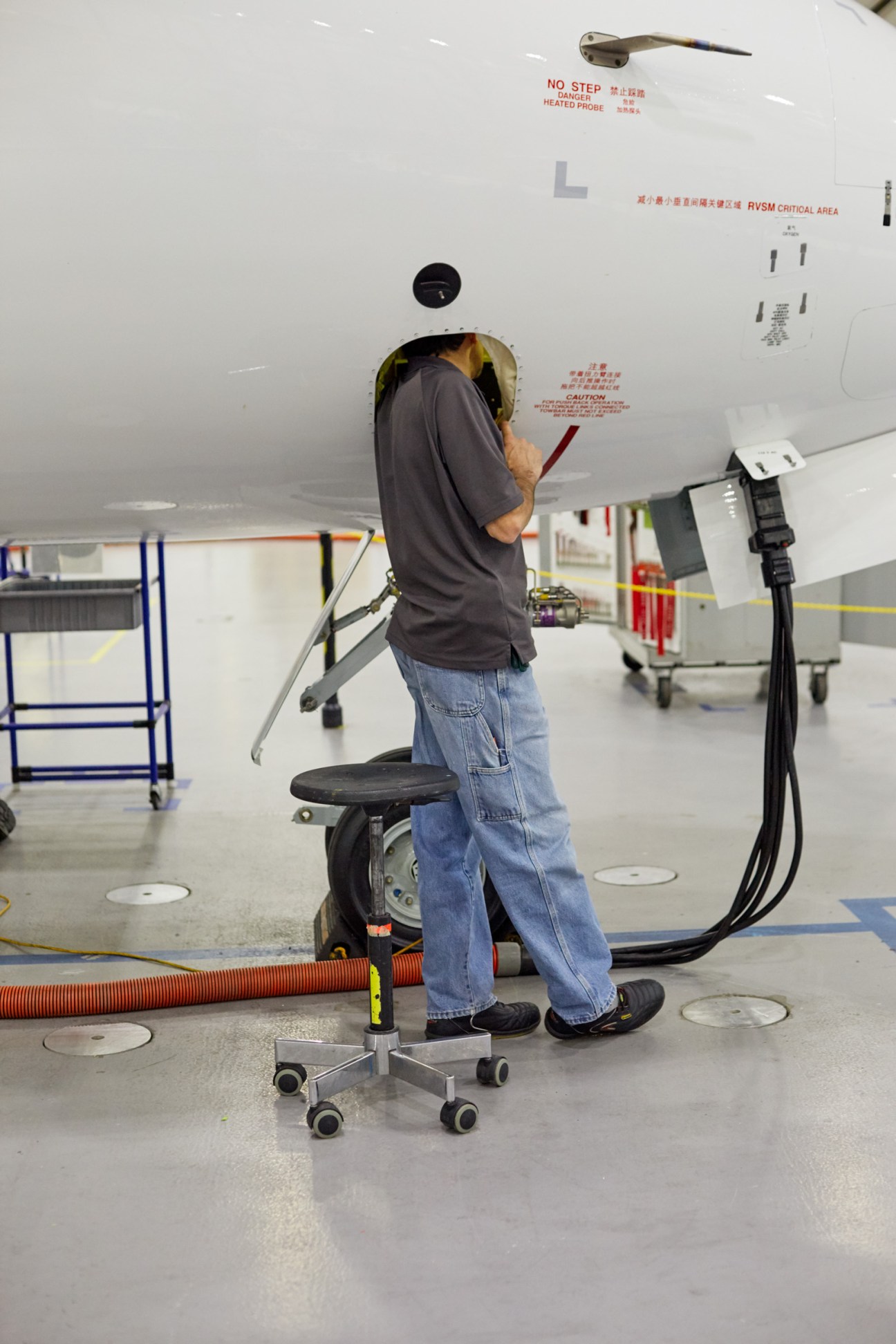 Technician working on aircraft underside in Bombardier production facility