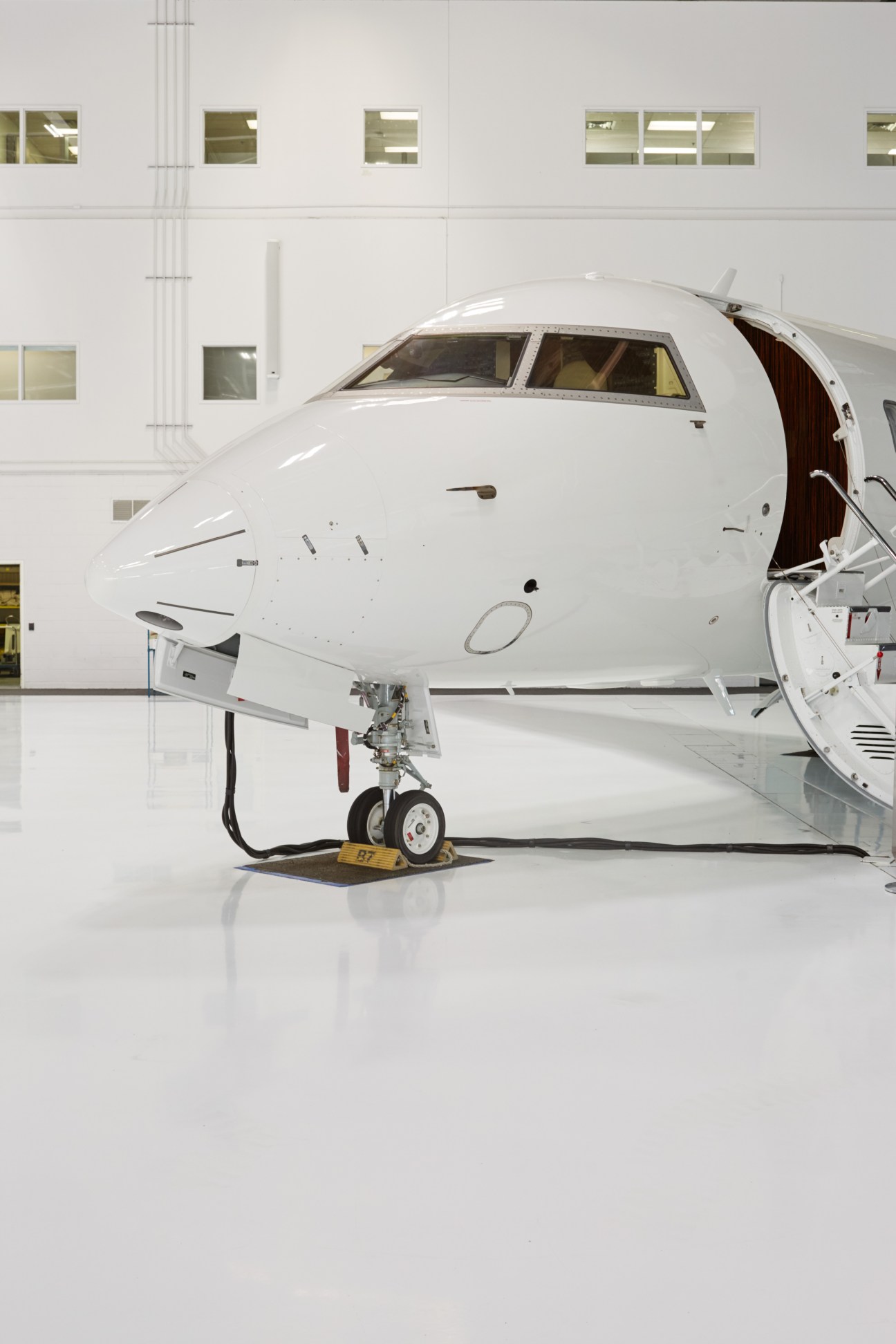 White Bombardier CRJ Series aircraft in hangar with open door