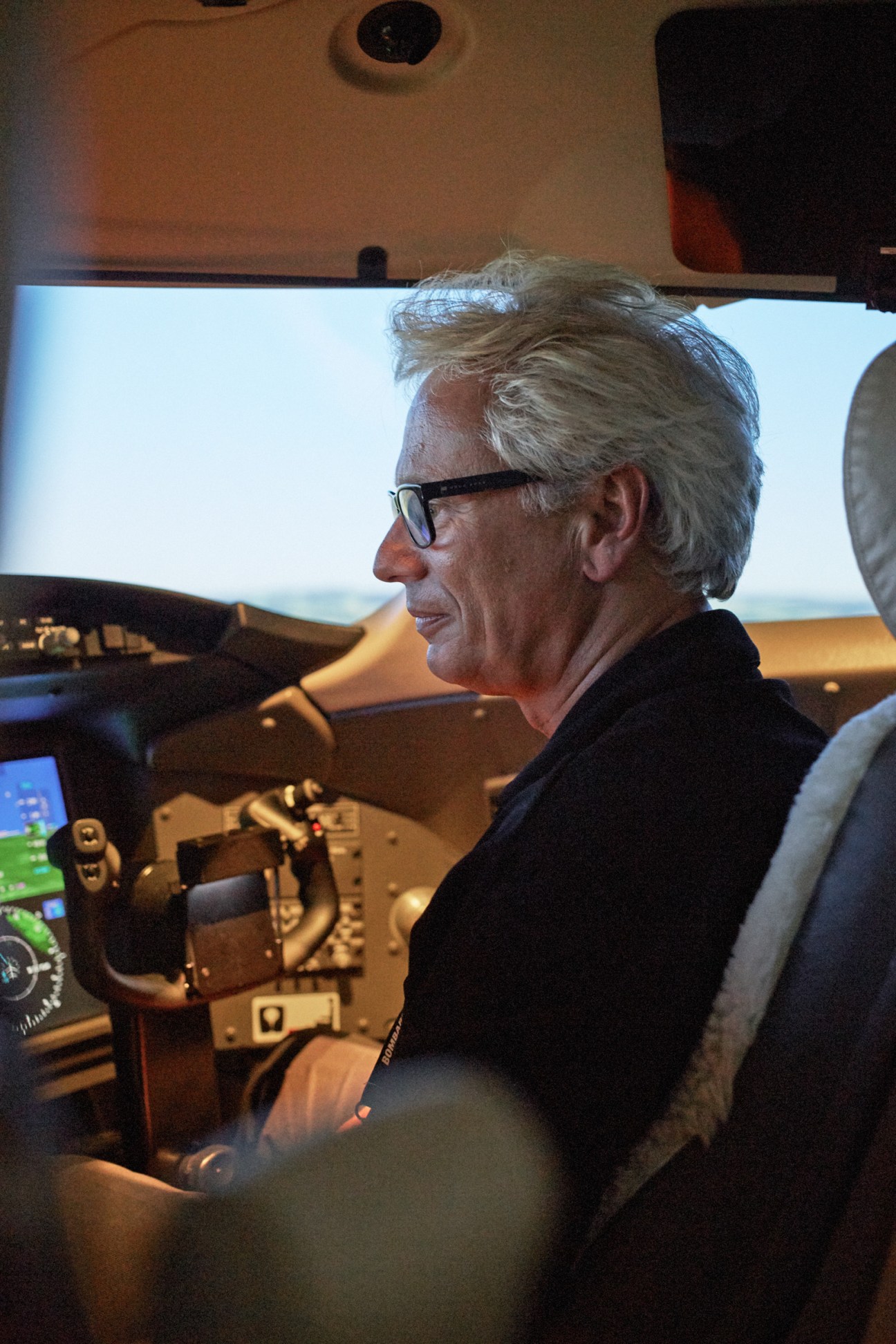 Robert Foucault sits in an aircraft cockpit wearing glasses and a dark jacket