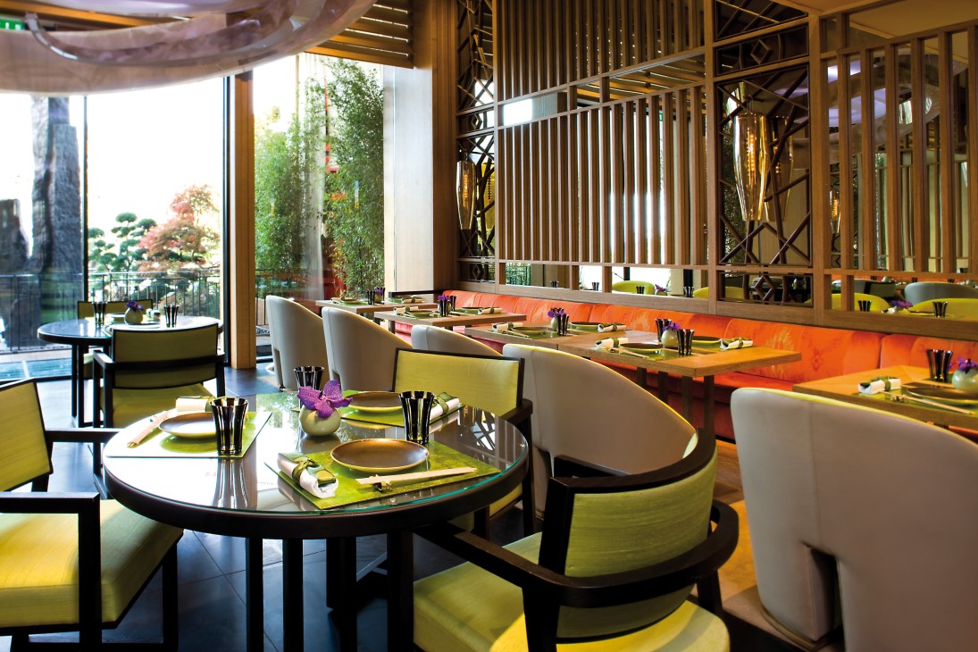 Modern Yoshi restaurant interior with lime green chairs, wooden lattice screens, and views of Monaco.