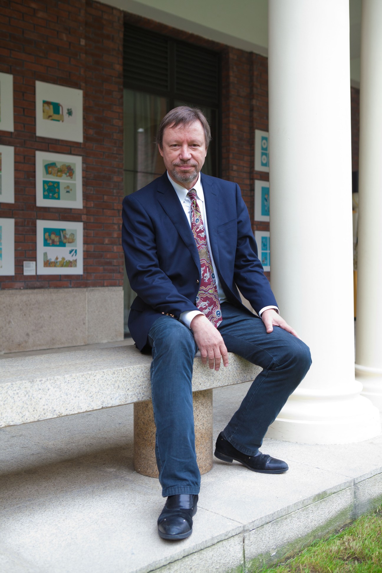 Willem Burgers, dean of faculty at Nordic International Management Institute, sitting on steps outside a brick building.