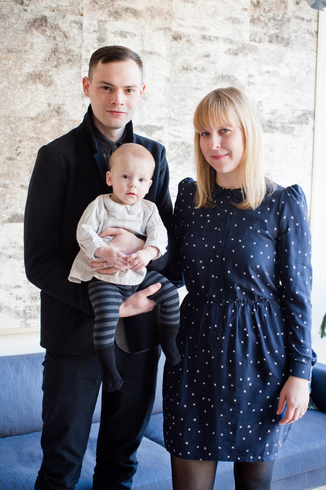 Mjölk owners John Baker and Juli Daoust stand with their young daughter against a white brick wall.