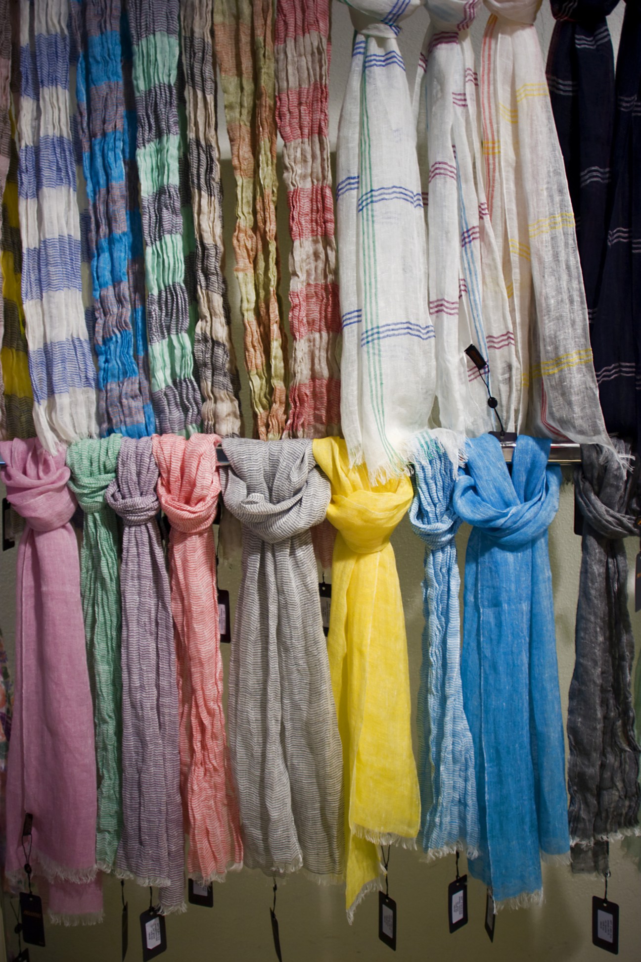 Colorful scarves displayed on hangers at Arianna, featuring striped and checked patterns in various hues.