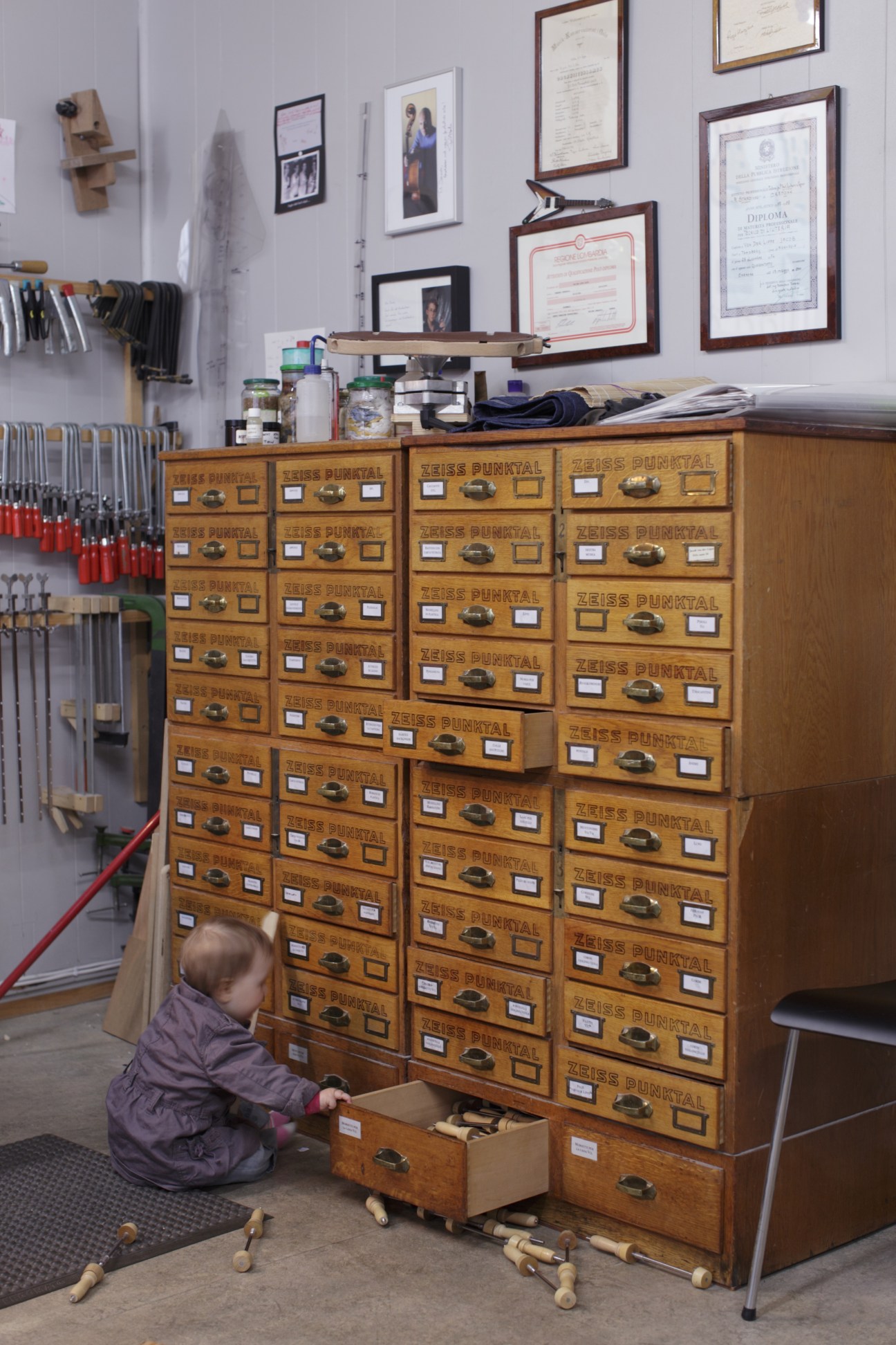 Child exploring a wooden Zeiss Punktal cabinet in Jacob von der Lippe's violin maker workshop.