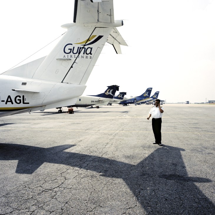 Gunas Airlines aircraft at Kathmandu airport with domestic route planes parked on tarmac.