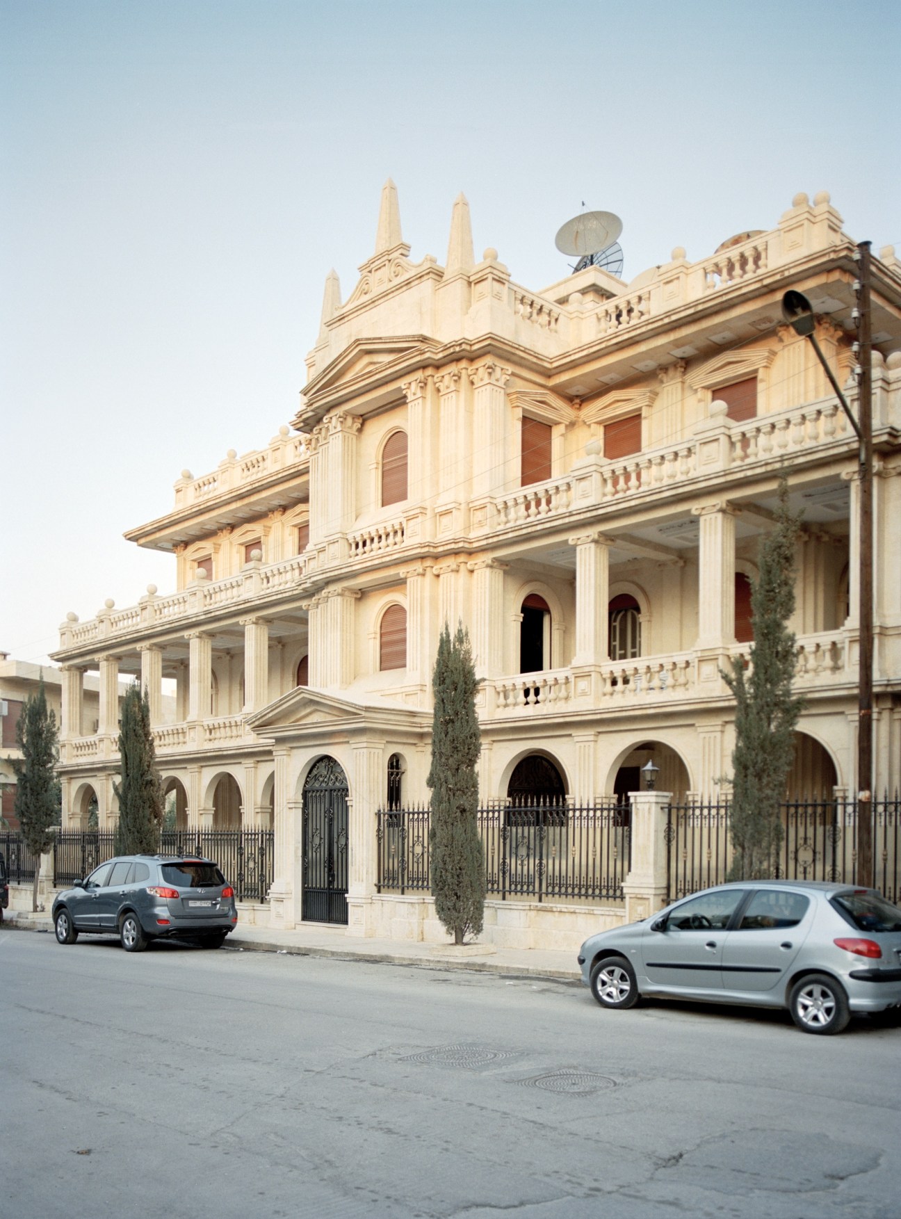 Cream-colored neoclassical villa with multiple stories, columns, and ornamental details near Aleppo University.