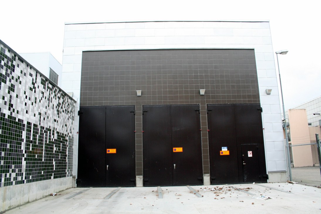 Modern waste collection station building with black doors and white upper facade in Stockholm.