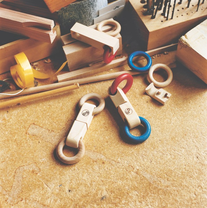 Mastro Geppetto wooden toy grips with colorful rings displayed on a workshop table with tools.