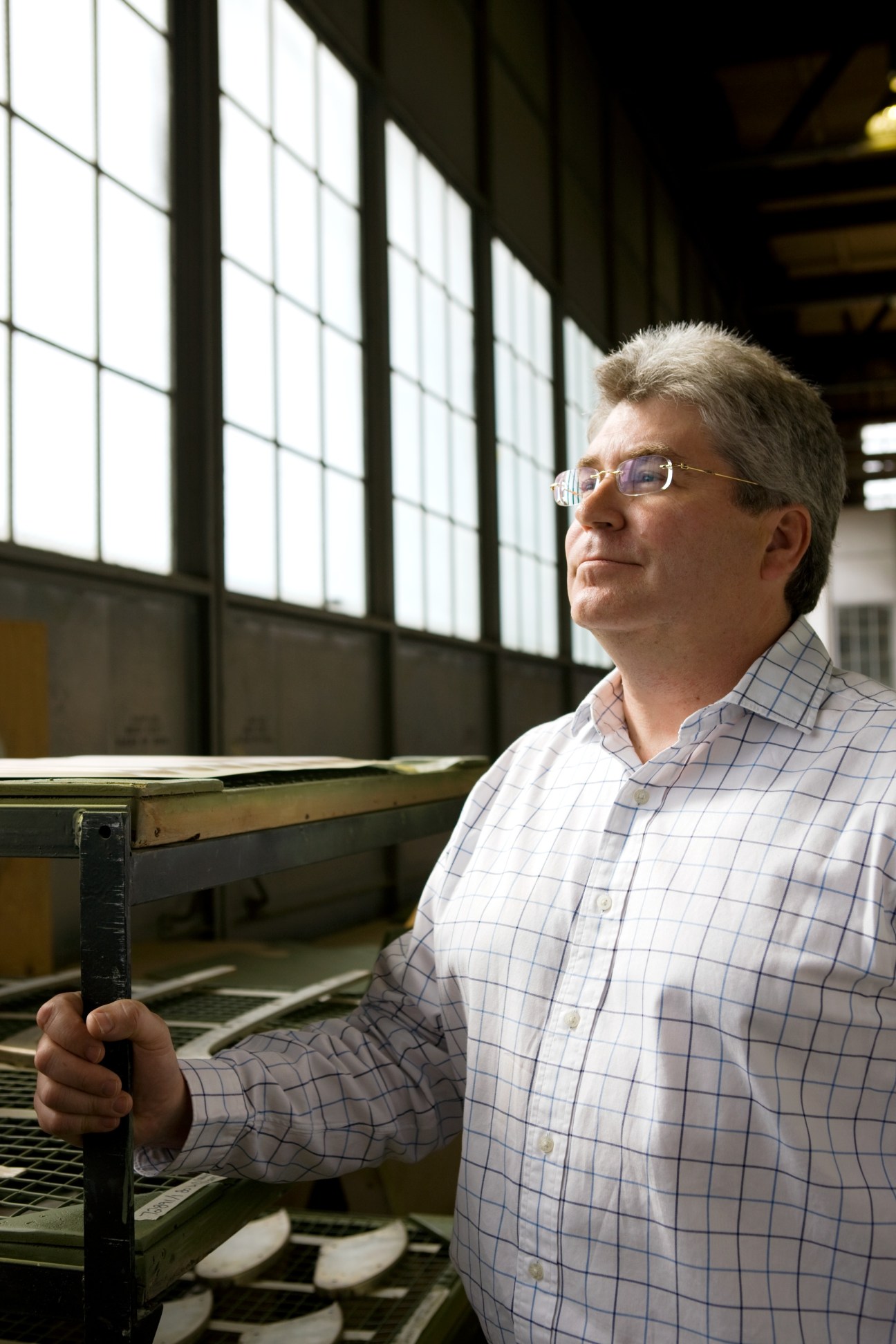 Rob Mauracher, vice president of business development at Viking Air, stands in an aircraft manufacturing facility holding a metal component.