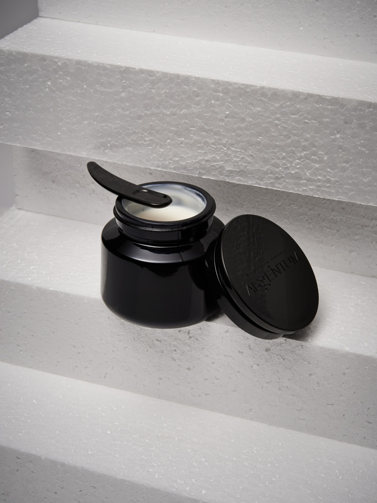 Argentum La Potion Infinie face cream in dark pot with tight lid and black applicator spoon.