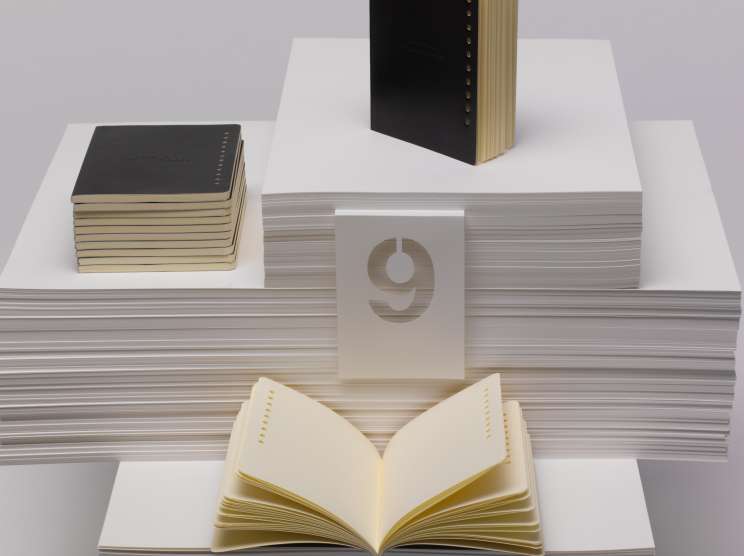 Nava Design stationery set featuring 12 monthly notebooks with punch-holes denoting each month, artfully arranged on stacked paper.