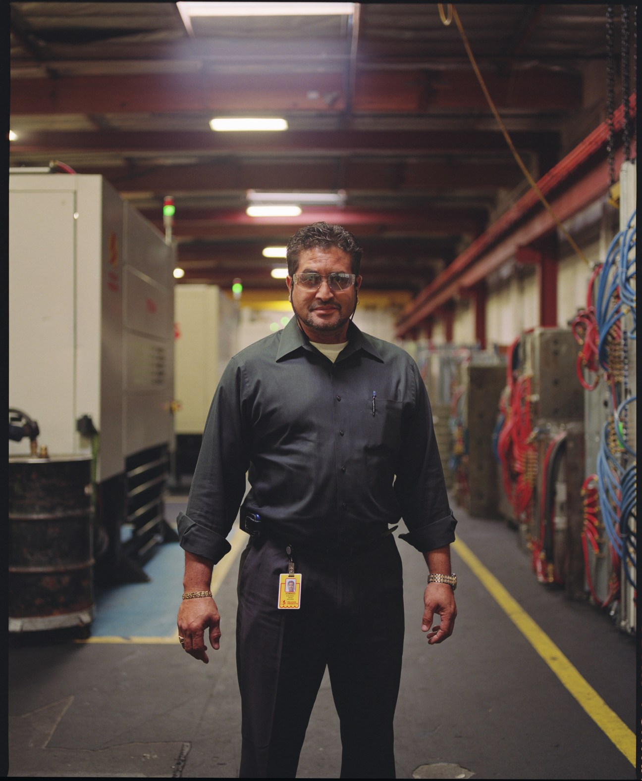Domingo Acevedo, case moulding team leader, stands in Pelican's factory floor wearing a dark work shirt and ID badge.