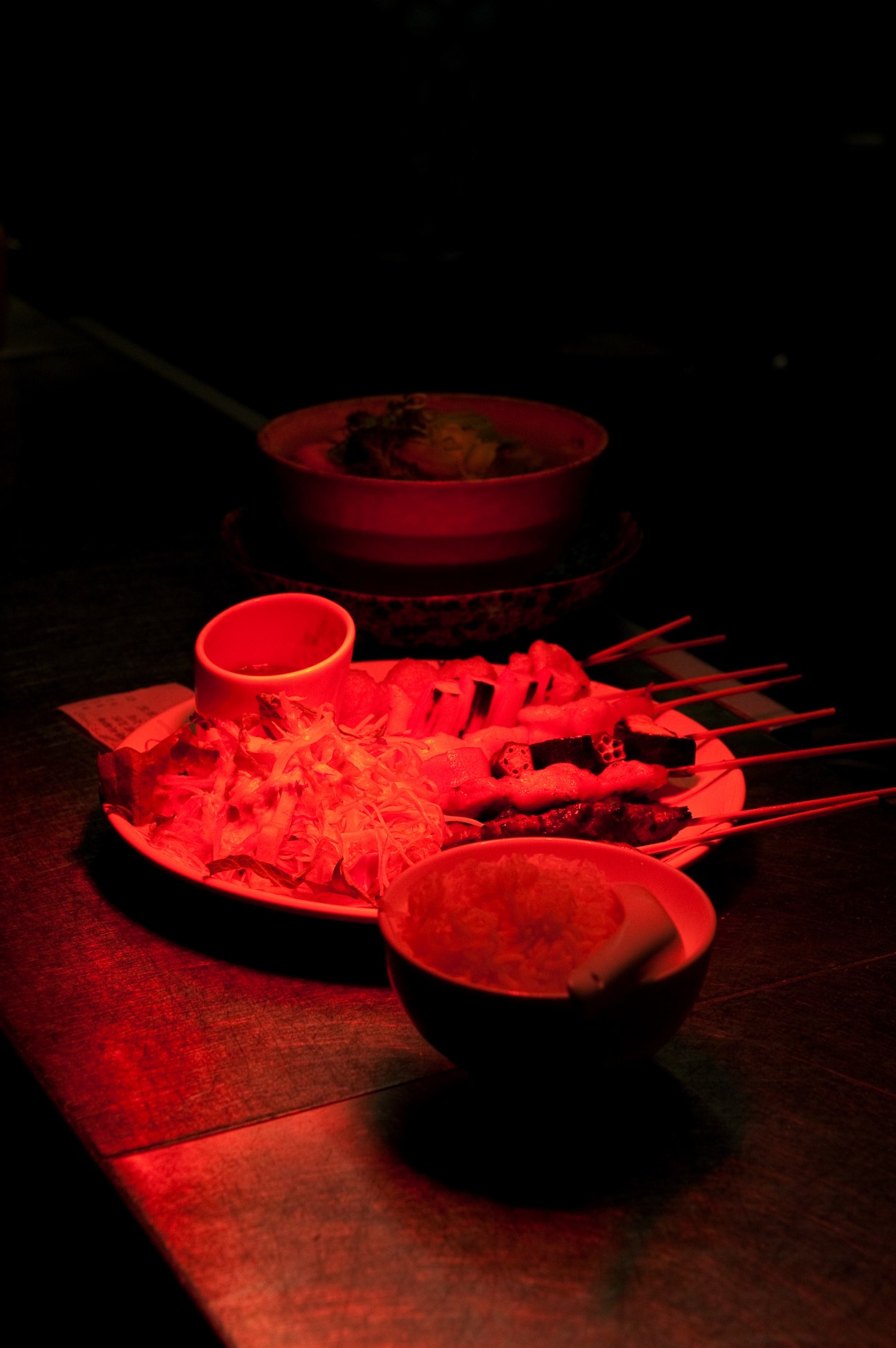 Ra'mein noodle dish with red bowls and chopsticks illuminated in red light