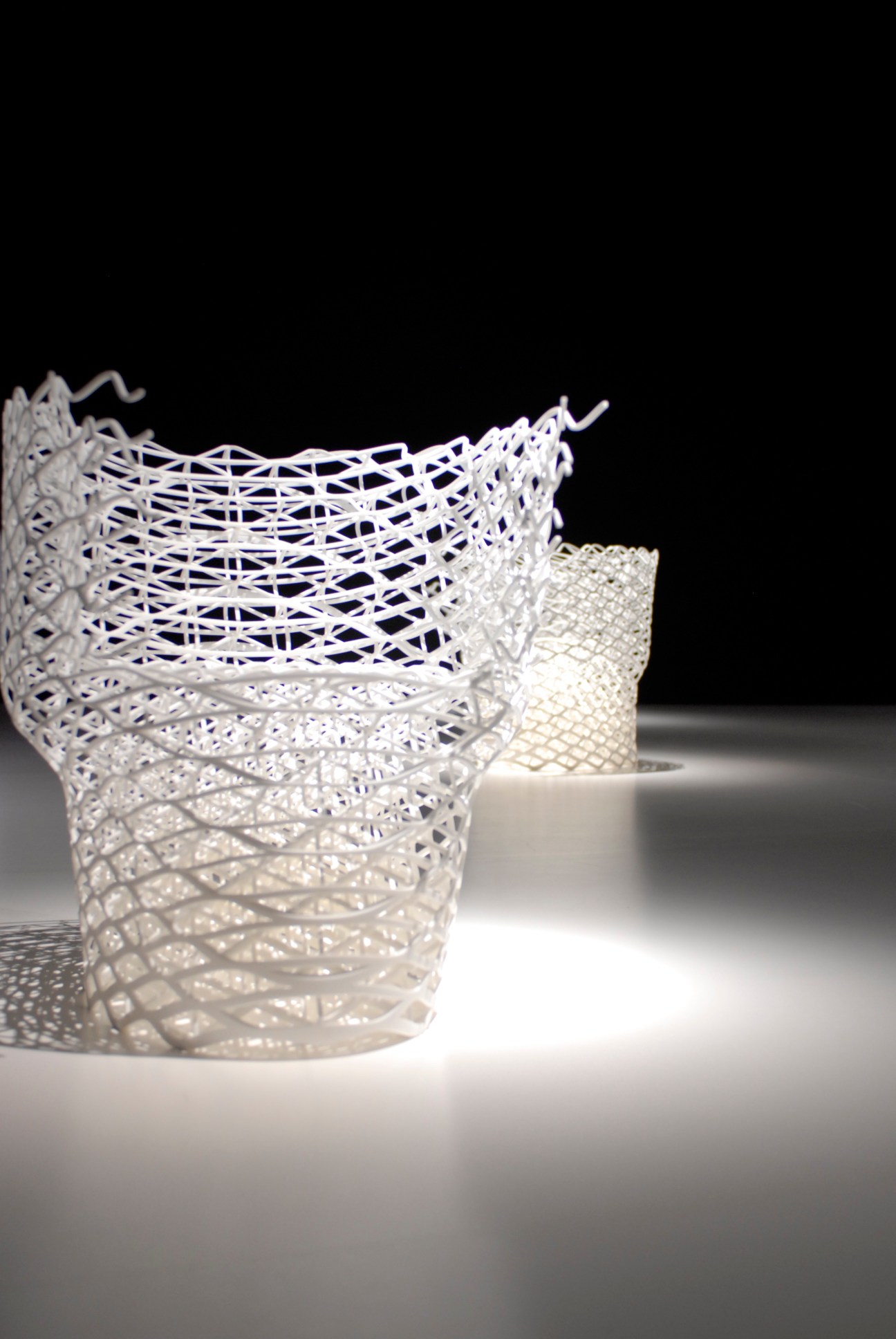 White latticed chair with an organic, diamond-inspired geometric structure against a black background.