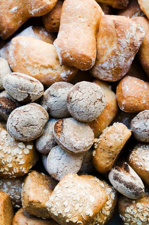 Assorted freshly baked Finnish breads with flour dusting and oat toppings displayed together.