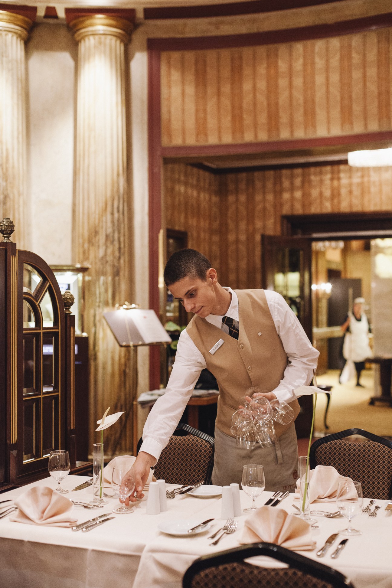 A server arranges glassware at a formally set dining table in Hotel Bristol's restaurant.