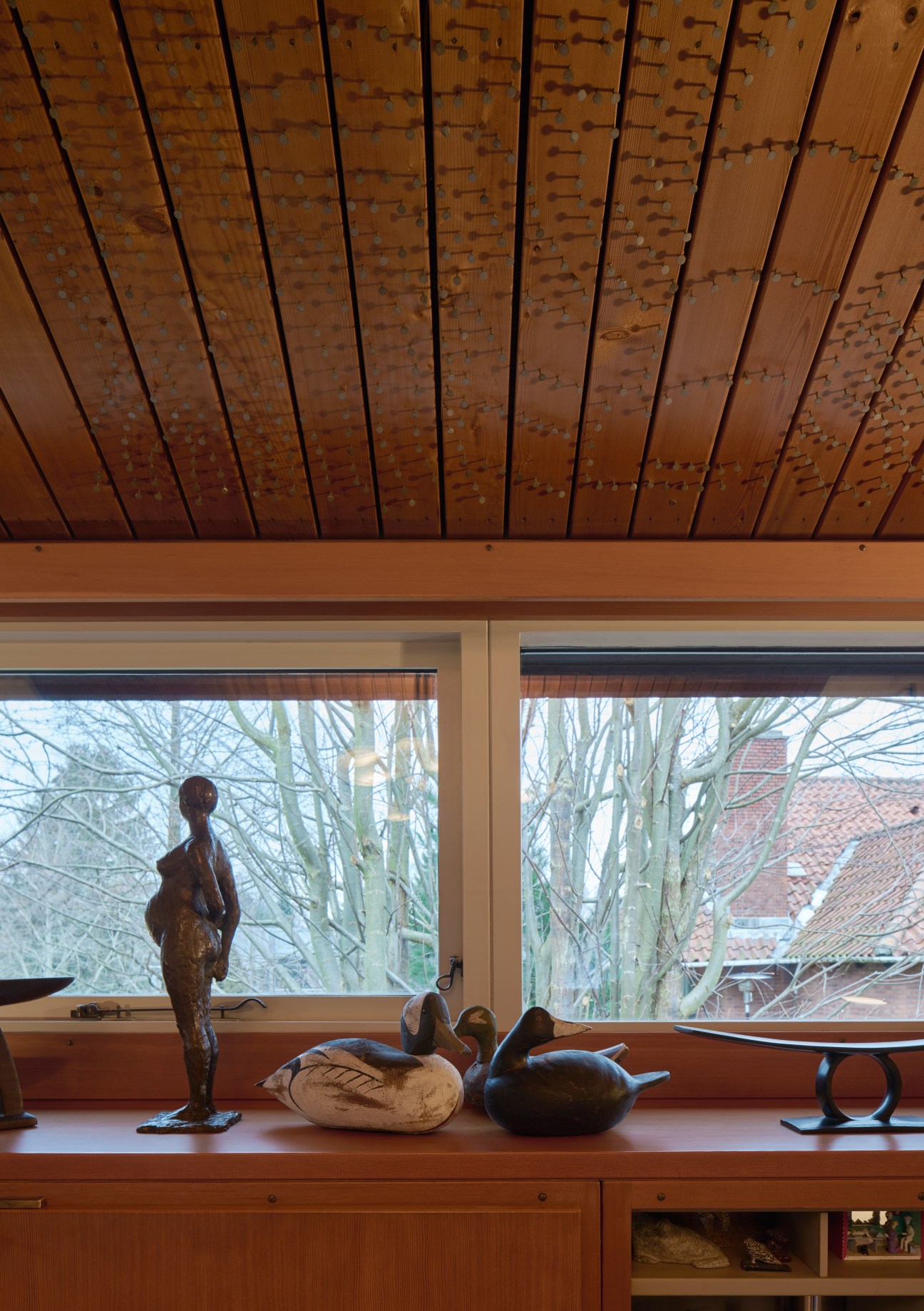 Wood-paneled ceiling with exposed nails and metal fasteners in a geometric pattern.