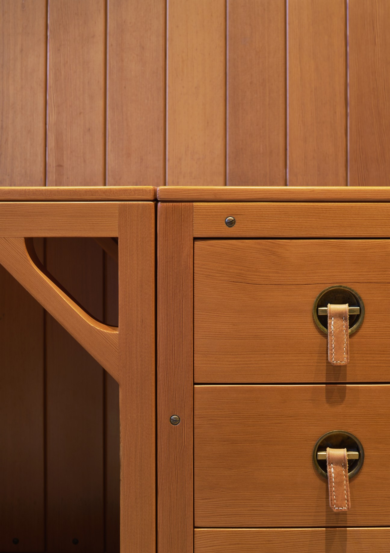Wooden cabinet with leather handles against panelled wall in Børge Mogensen's home.
