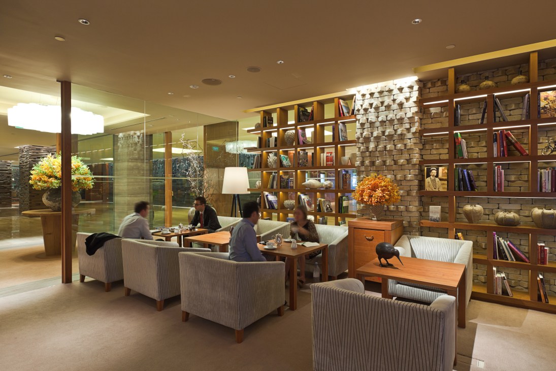 Grand Hyatt Singapore's lobby lounge with wooden bookshelves, striped armchairs, and guests conversing.