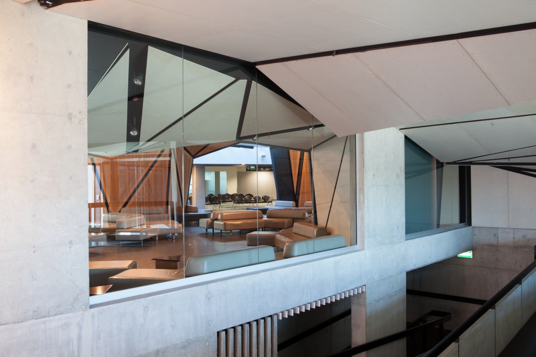 Wellington International Airport's modern interior with angular copper-clad structure, glass partitions, and wooden ceiling panels.