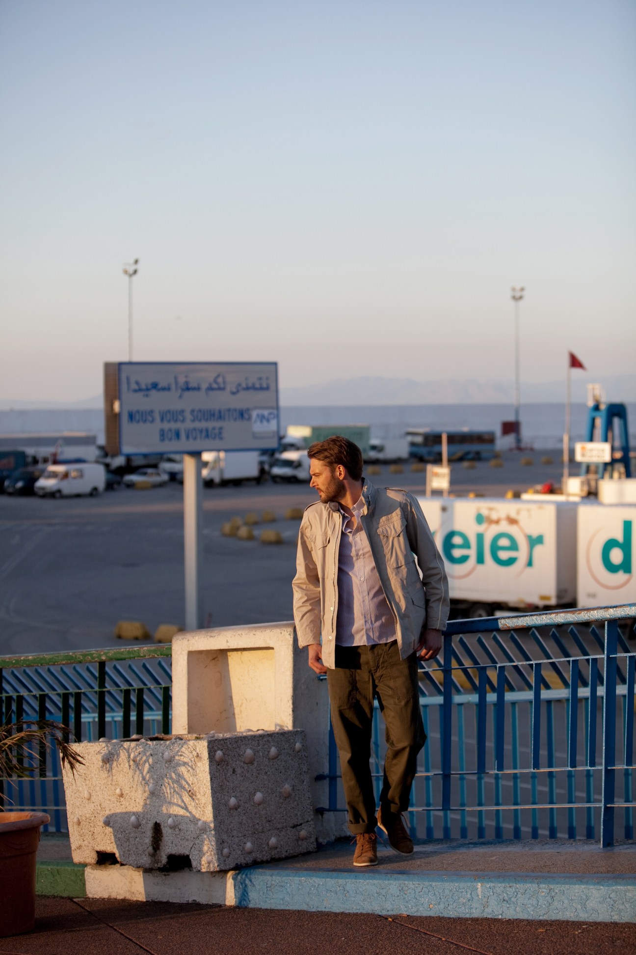Man wearing Visvim jacket and shirt with Beams+ trousers and Shöfolk shoes standing at Tangier waterfront.