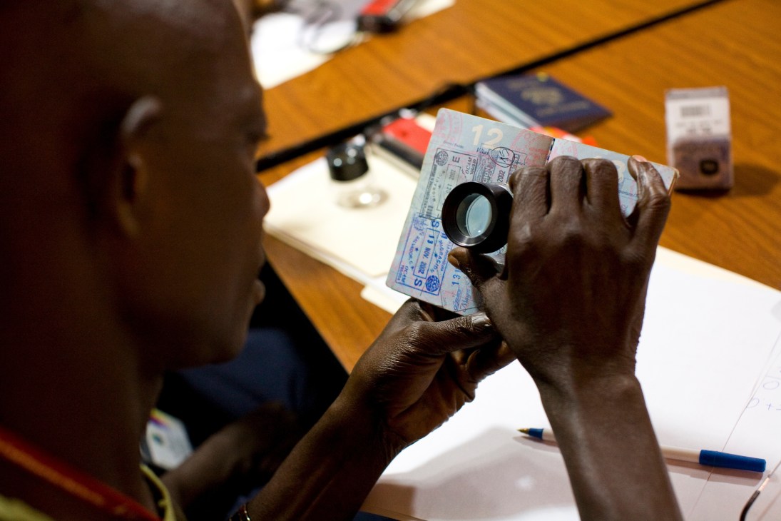 A TSA trainer demonstrates ultraviolet lamp technique to inspect a passport for security features and forgeries.