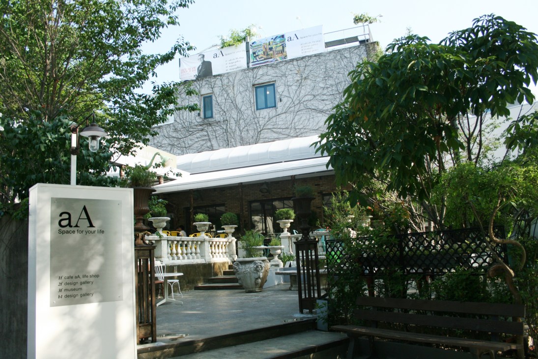 aA design museum entrance in Seoul with signage, outdoor seating area, and modern building facade.