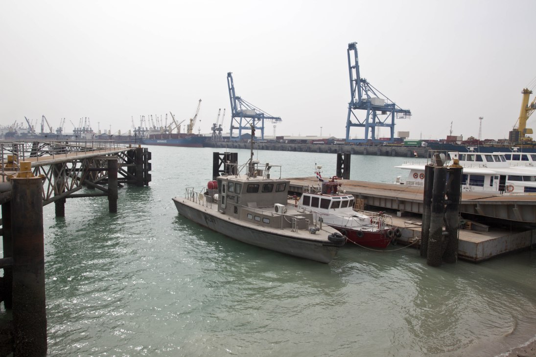 Industrial port facility with cargo cranes, moored vessels, and waterfront infrastructure at Um Qasr Port.