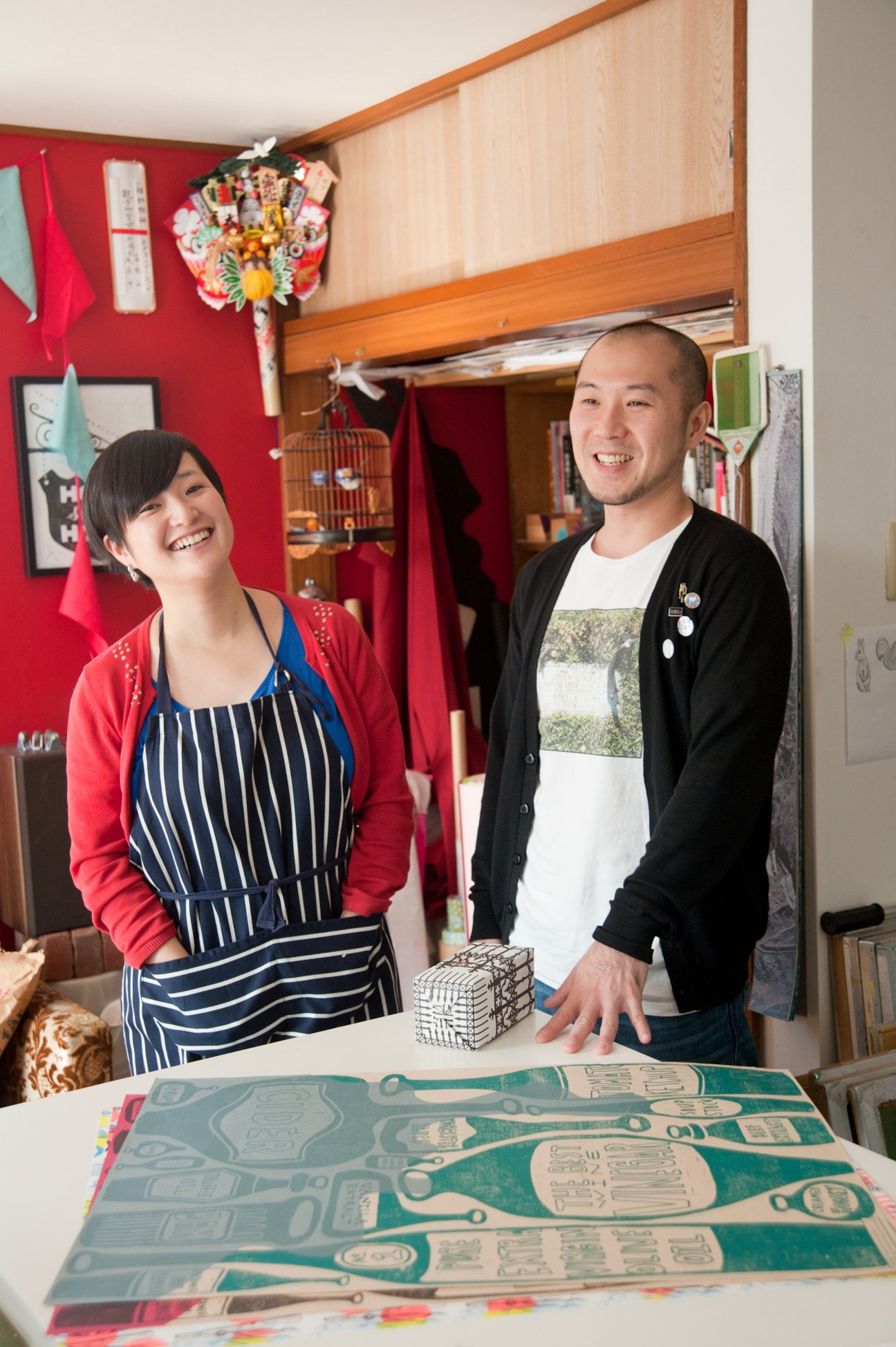 Hiromi and Mitsunori Asakura standing in their studio with wrapping paper designs displayed on the table.