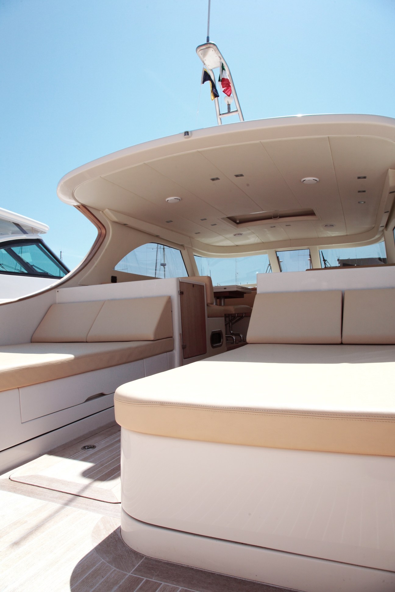 Luxury yacht interior with cream-colored sunbeds and curved ceiling under clear blue sky.