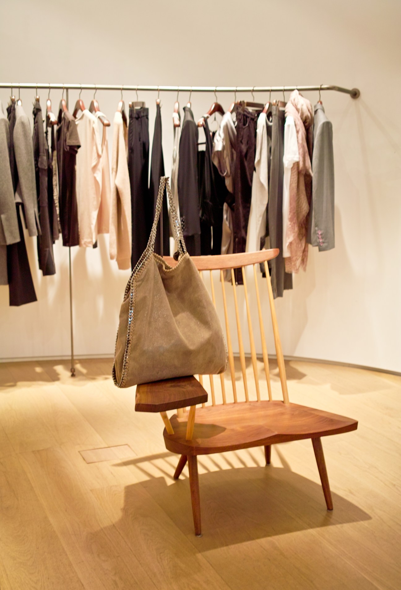 Stella McCartney women's display at Boon The Shop featuring clothing on a rail and a handbag on a wooden chair.