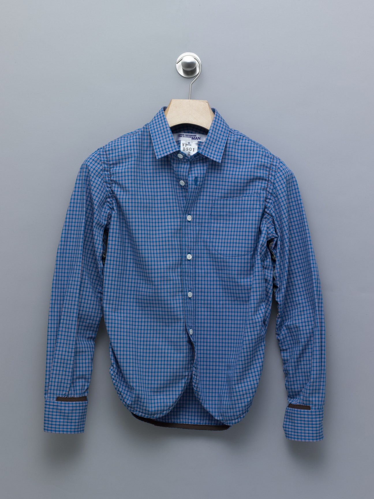 Blue checked button-up shirt on hanger labeled Junya Watanabe Man Femme.