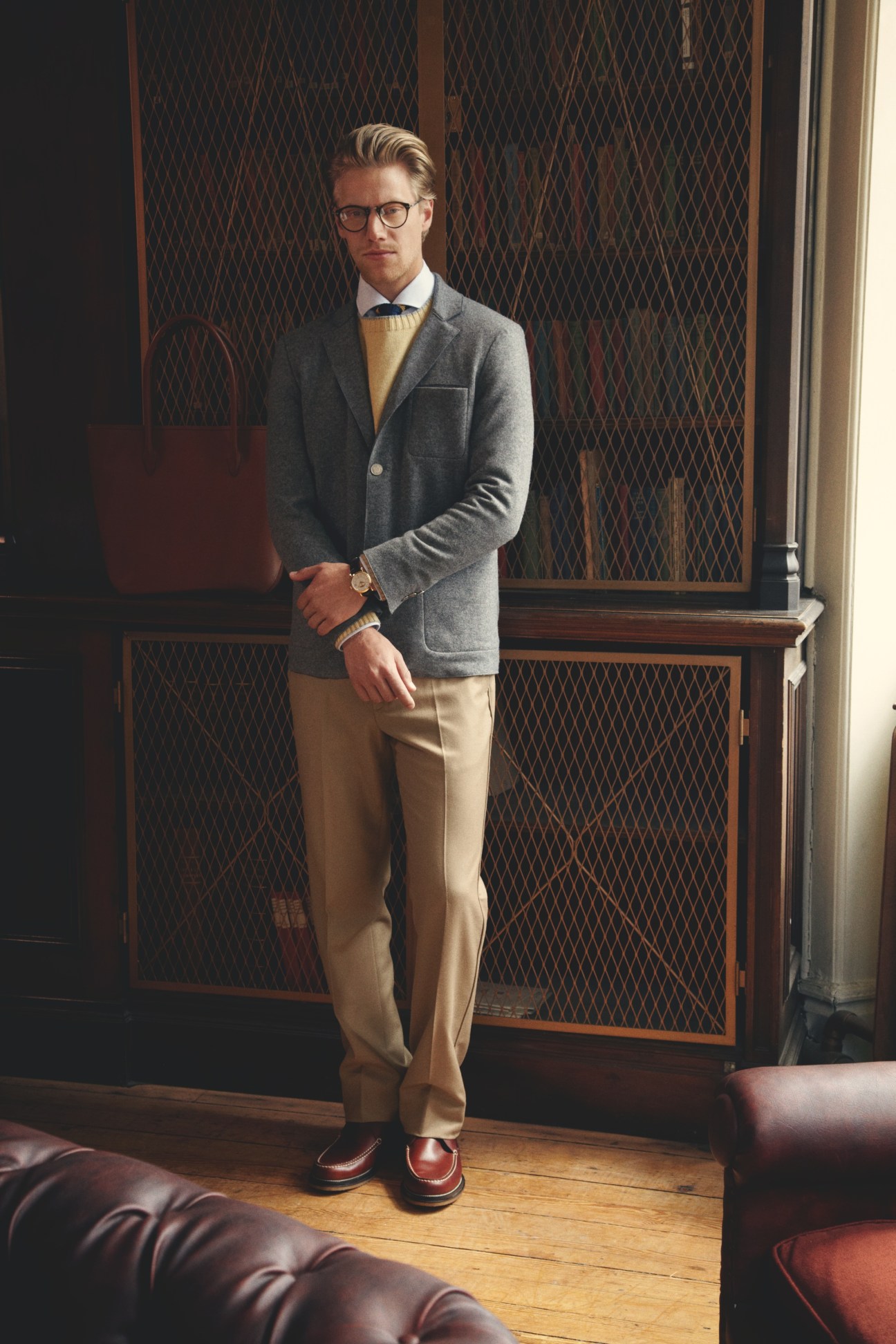 Man wearing Dunhill jacket, Brunello Cucinelli jumper and shirt, Ralph Lauren tie, and Salvatore Ferragamo trousers with Oliver Peoples glasses and Patek Philippe watch.