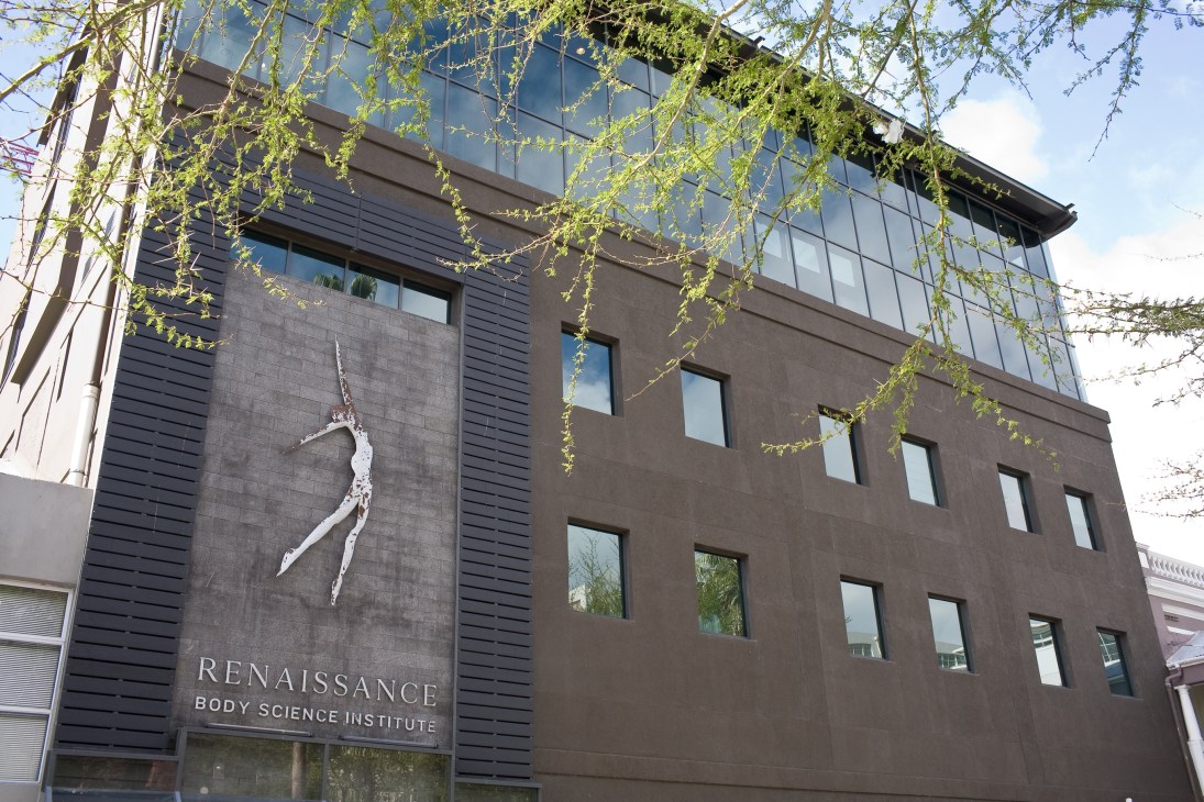 Modern dark-facade building with Renaissance Body Science Institute signage and sculptural white figure installation.