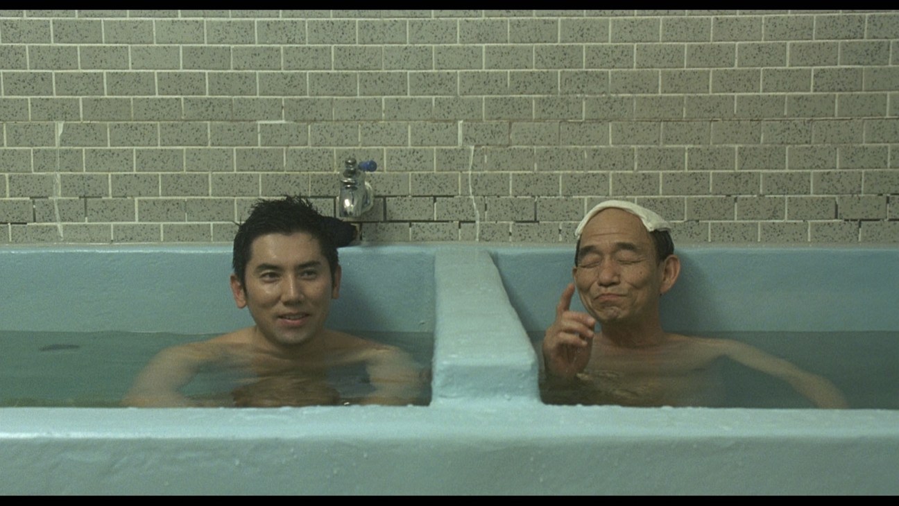 Two men bathing together in a tiled public bath in a scene from the film Departures.