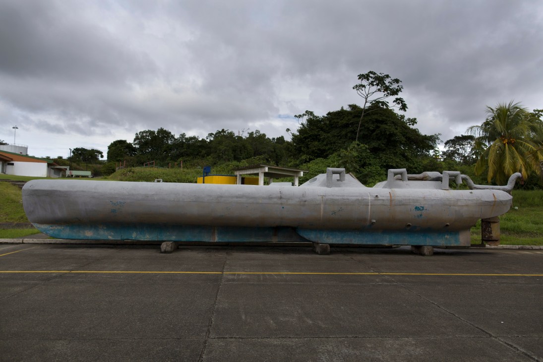 A captured submarine used for drug smuggling displayed on a concrete pad with rainforest vegetation in the background.