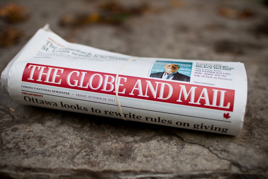 The Globe and Mail newspaper rolled on concrete surface, dated Friday, October 28, 2011.