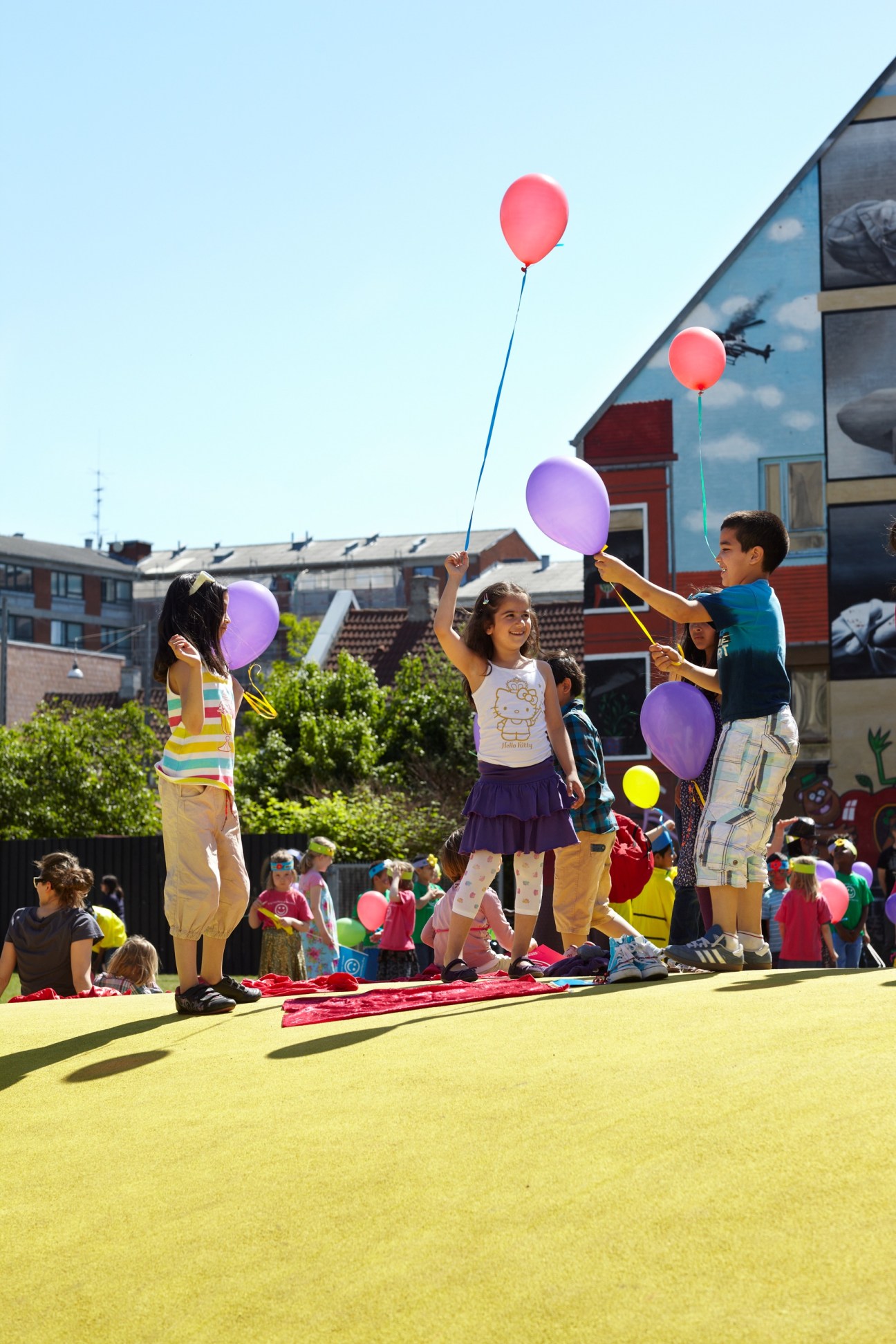 Children holding colorful balloons at an outdoor playground event in Copenhagen.