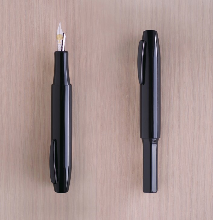Pentagon fountain pen by Industrial Facility with 18-carat gold nib, shown open and closed against wooden surface.