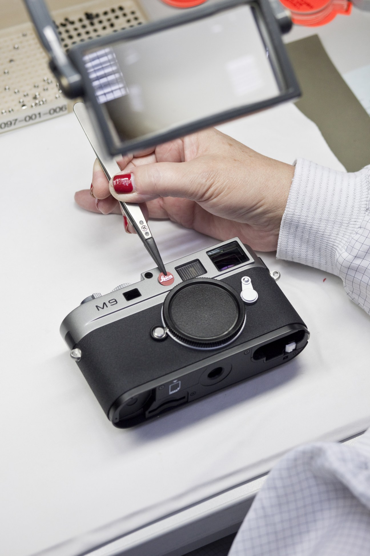 Hand holding stylus above Leica M9 camera during product inspection or demonstration.