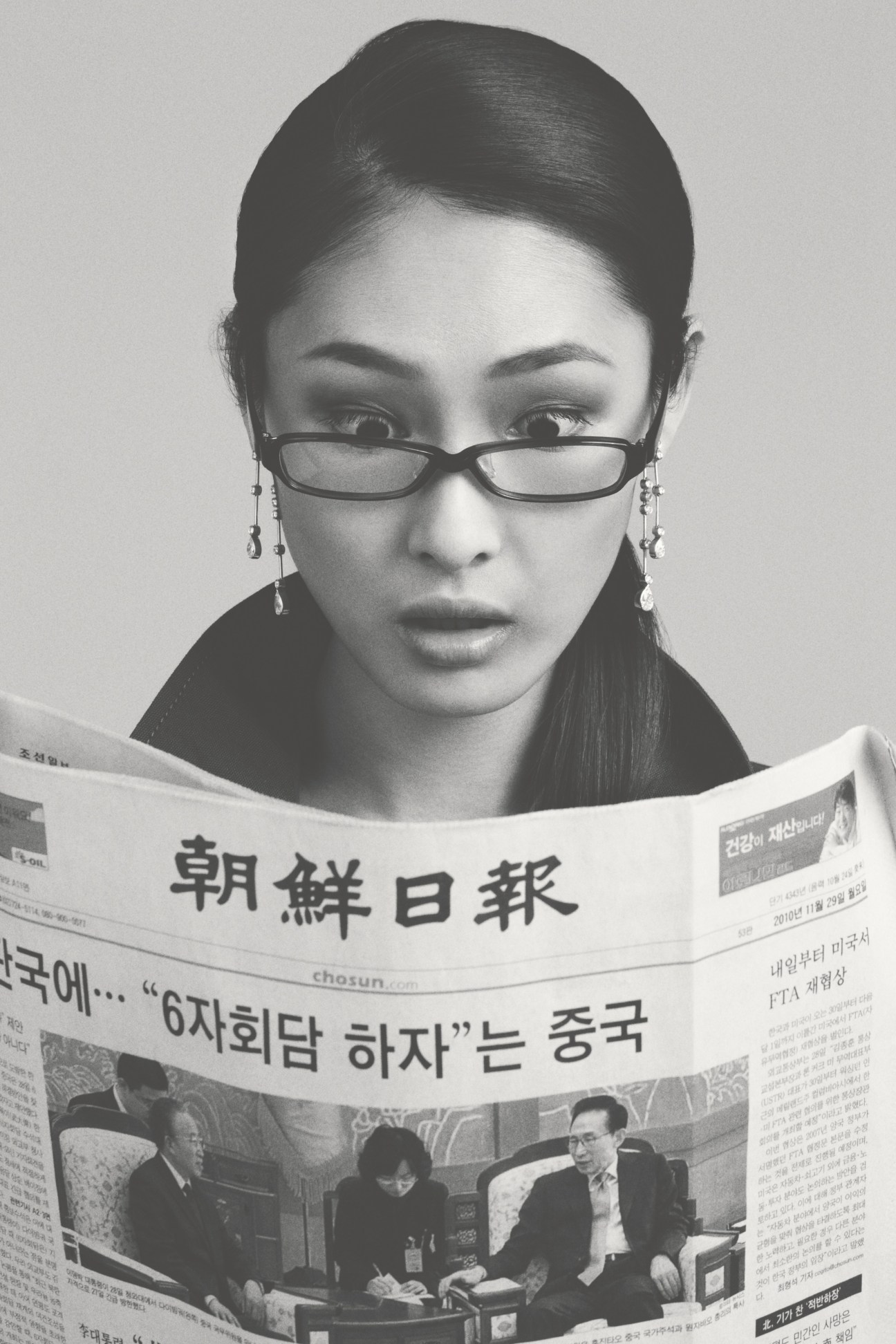 Person wearing 999.9 NP-104 glasses and Chanel earrings, holding a Korean newspaper.